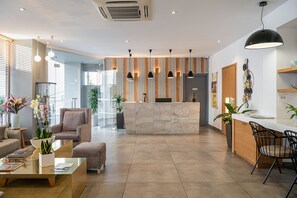 Un espace d’accueil moderne doté d’un comptoir en marbre, de sièges et de luminaires suspendus.