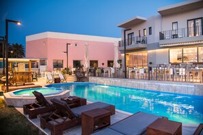 Un espace piscine avec des chaises longues et un bar.
