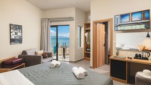 A hotel room with a bed, a desk, a chair, a wardrobe, and a view of the sea. - Elia Agia Marina Hotel (Chania)
