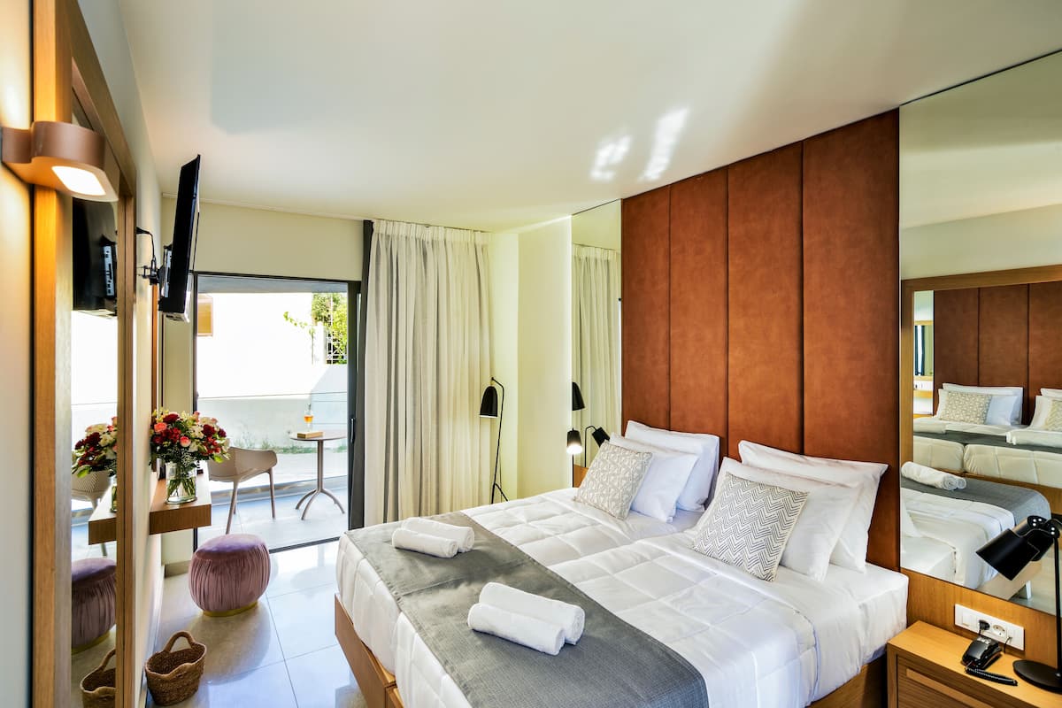 Habitación de hotel moderna con una cama grande, una mesita de noche, un espejo y vistas al exterior.