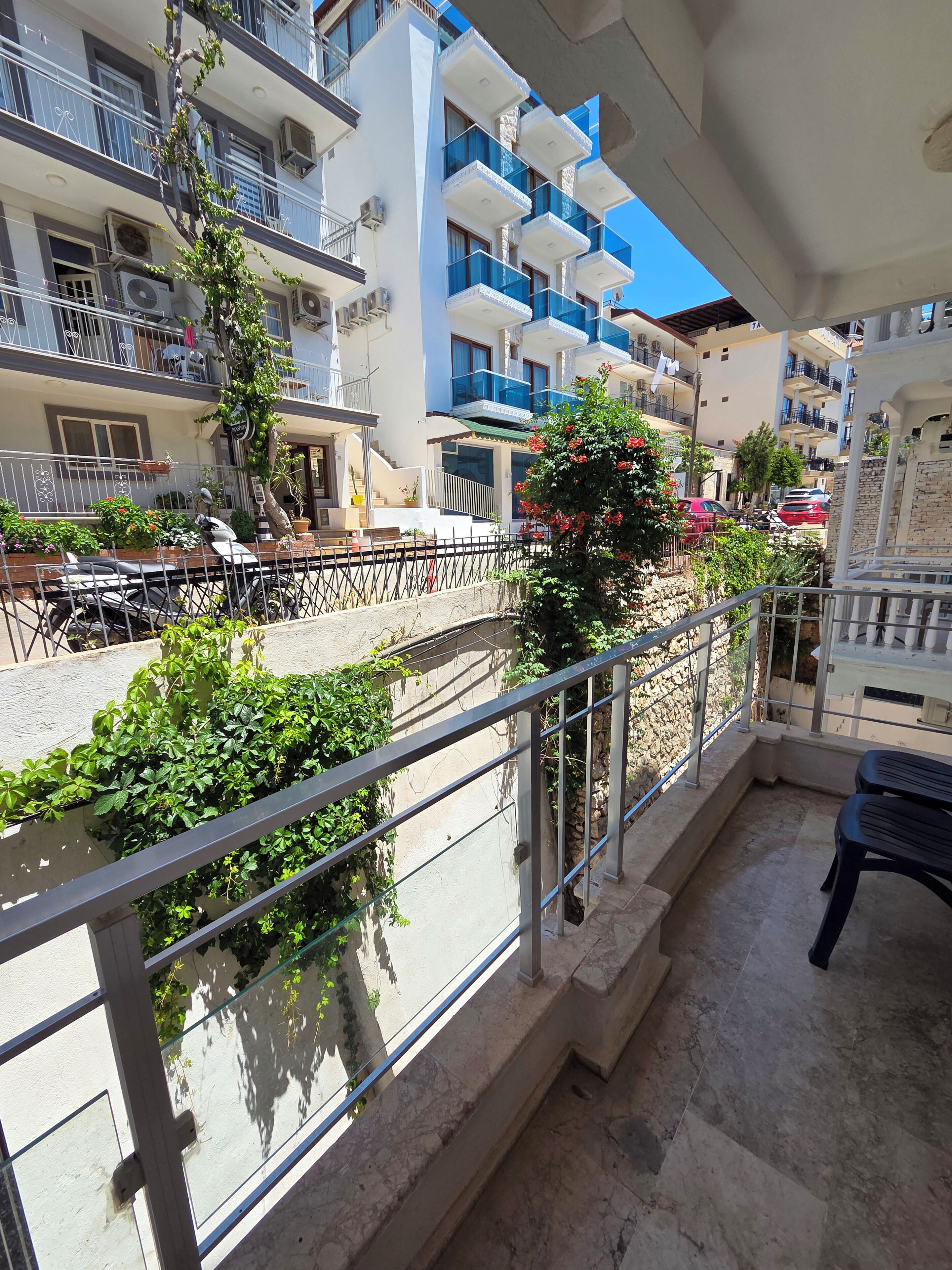 A balcony with a metal railing, a potted plant, and a scooter.