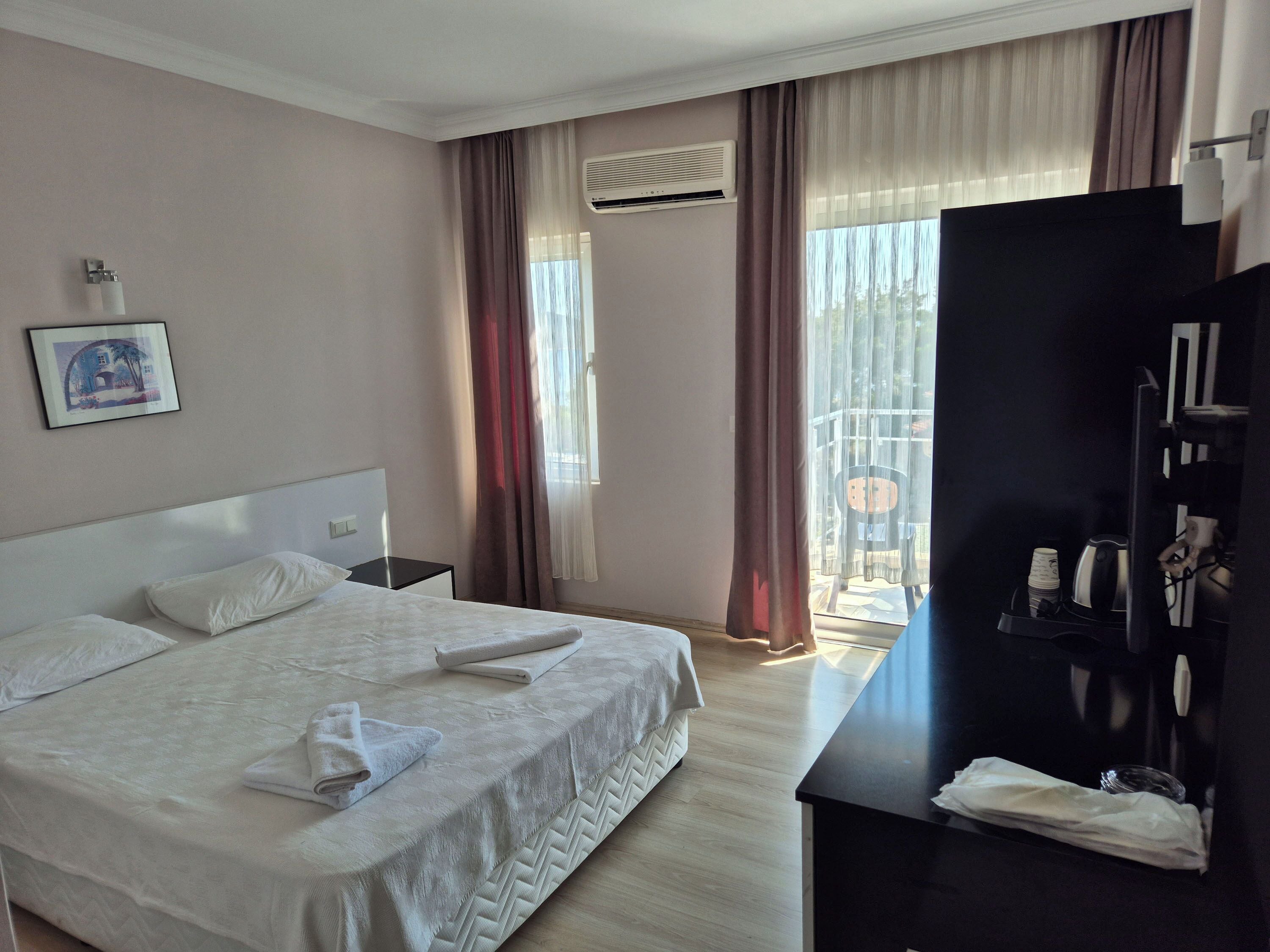 A hotel room with a bed, a desk, a chair, and a window with curtains.
