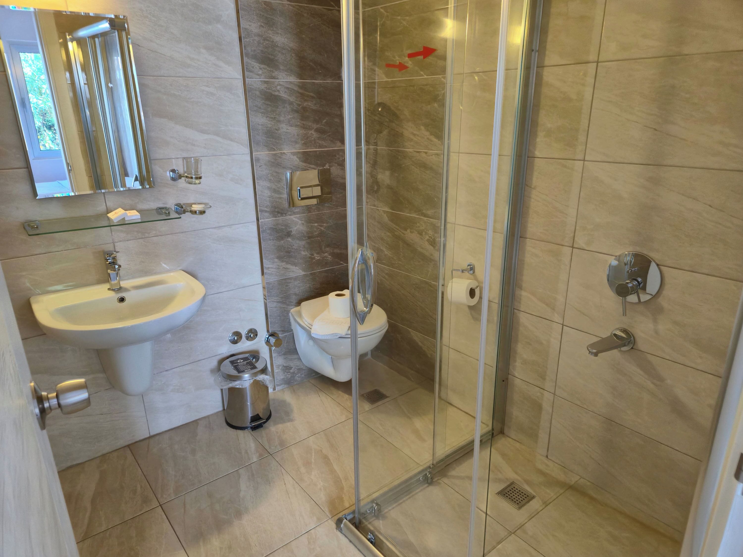 Ein modernes Badezimmer mit einer gläsernen Duschkabine, einem Waschbecken und einer Toilette.
