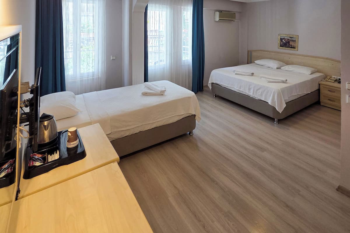 Quarto de hotel com duas camas, uma mesa, televisão e máquina de café.