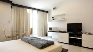A modern hotel room with a bed, a desk with a flat-screen TV, a microwave, and a coffee maker. - Tongtip Place (Bangkok)