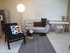 Una sala de estar moderna con un sofá, un sillón, una mesita y una lámpara.