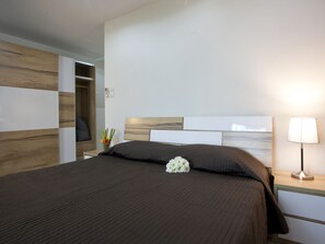 Habitación de hotel con cama, mesita de noche, lámpara y pared con diseño de paneles de madera.