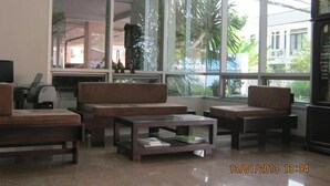 A spacious lobby with large windows, a sofa set, a coffee table, and a clock. - Tongtip Place (Bangkok)