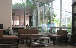 A spacious lobby with large windows, a sofa set, a coffee table, and a clock. - Tongtip Place (Bangkok)