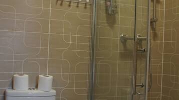 A bathroom with a toilet, sink, and glass shower enclosure.