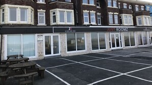 A row of townhouses with a black storefront labeled "JUST ROOMZ". - Hello Roomz (Blackpool)