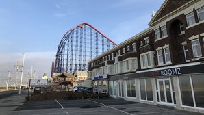 A hotel named 'Just Roomz' with a signboard, adjacent to a roller coaster. - Hello Roomz (Blackpool)