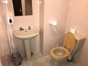 Un baño con lavamanos, inodoro y espejo.