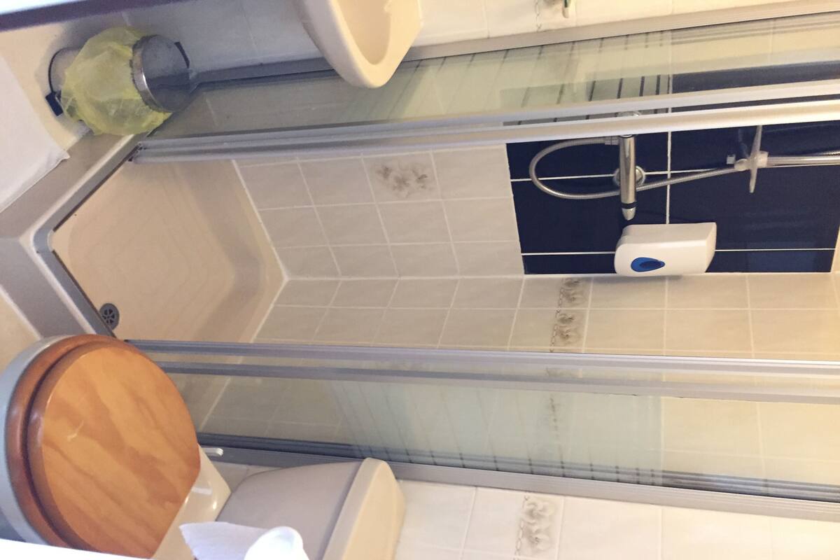 A bathroom with a glass shower enclosure, a toilet, and a sink.