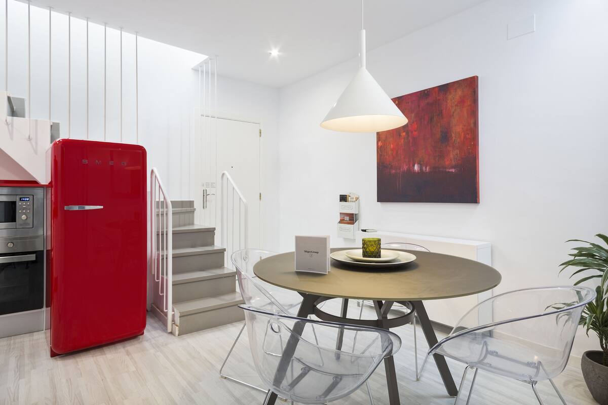 A modern kitchen with a red refrigerator, a microwave, and a staircase.