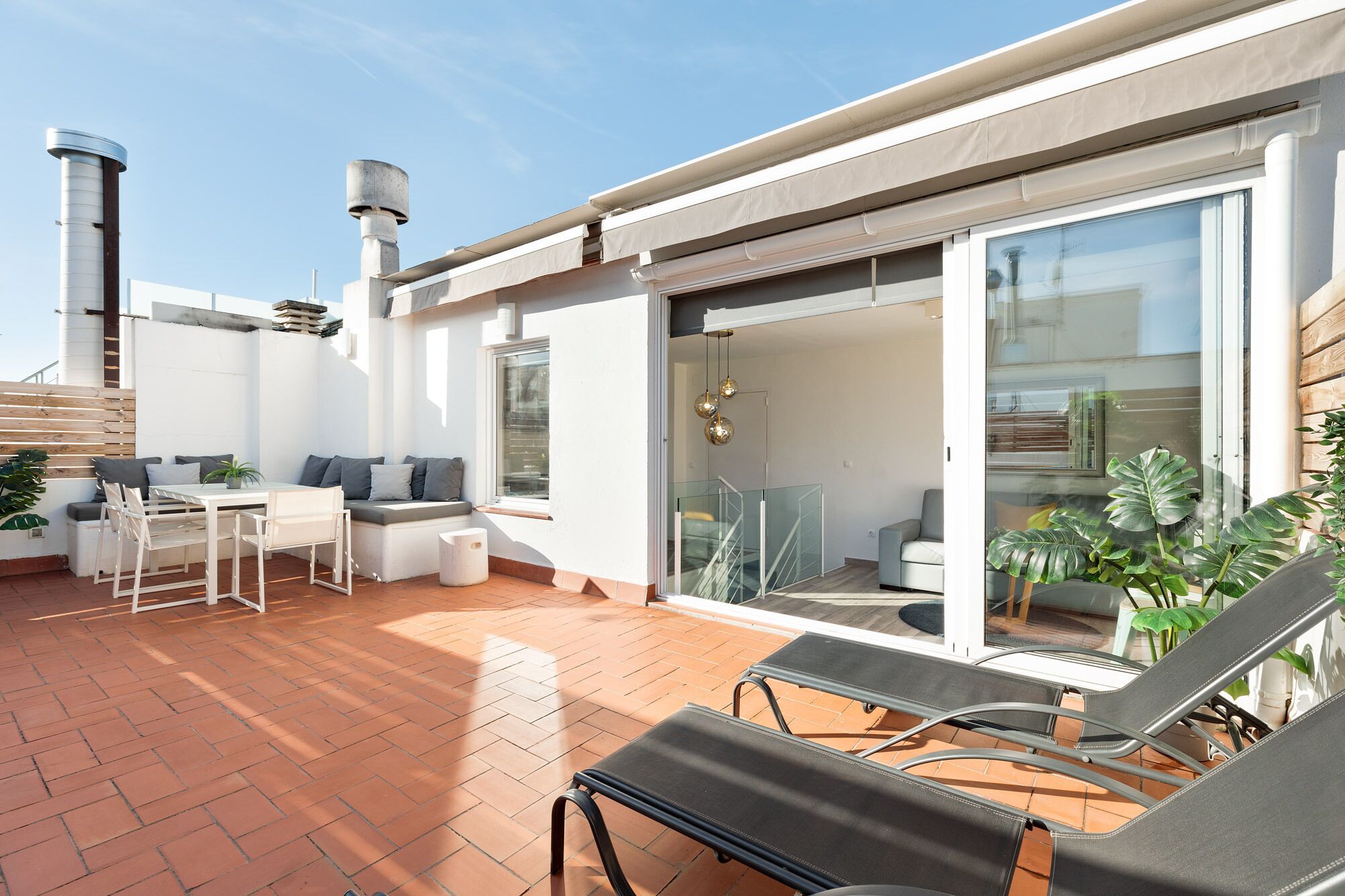 Une terrasse extérieure moderne, dotée d’un espace salon, d’une table et de fauteuils confortables.
