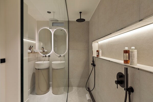 A modern bathroom with two sinks, a glass partition, and a shower area.