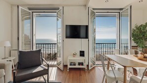 Un balcón con televisor, sofá, mesa de comedor y sillas.