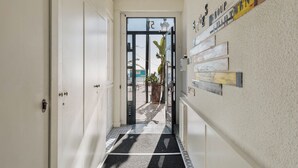 Un pasillo con piso de baldosas blanco y negro, una puerta con panel de vidrio y una pared con varios carteles e imágenes.