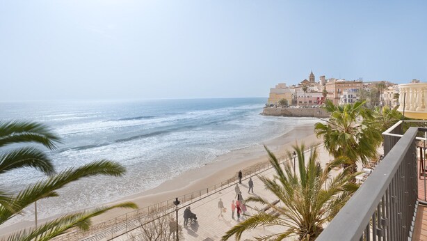 Un paisaje urbano costero con playa, paseo marítimo y edificios históricos.