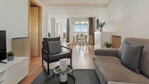 Una sala de estar moderna con un sofá, un sillón y una zona de comedor con una mesa y sillas.