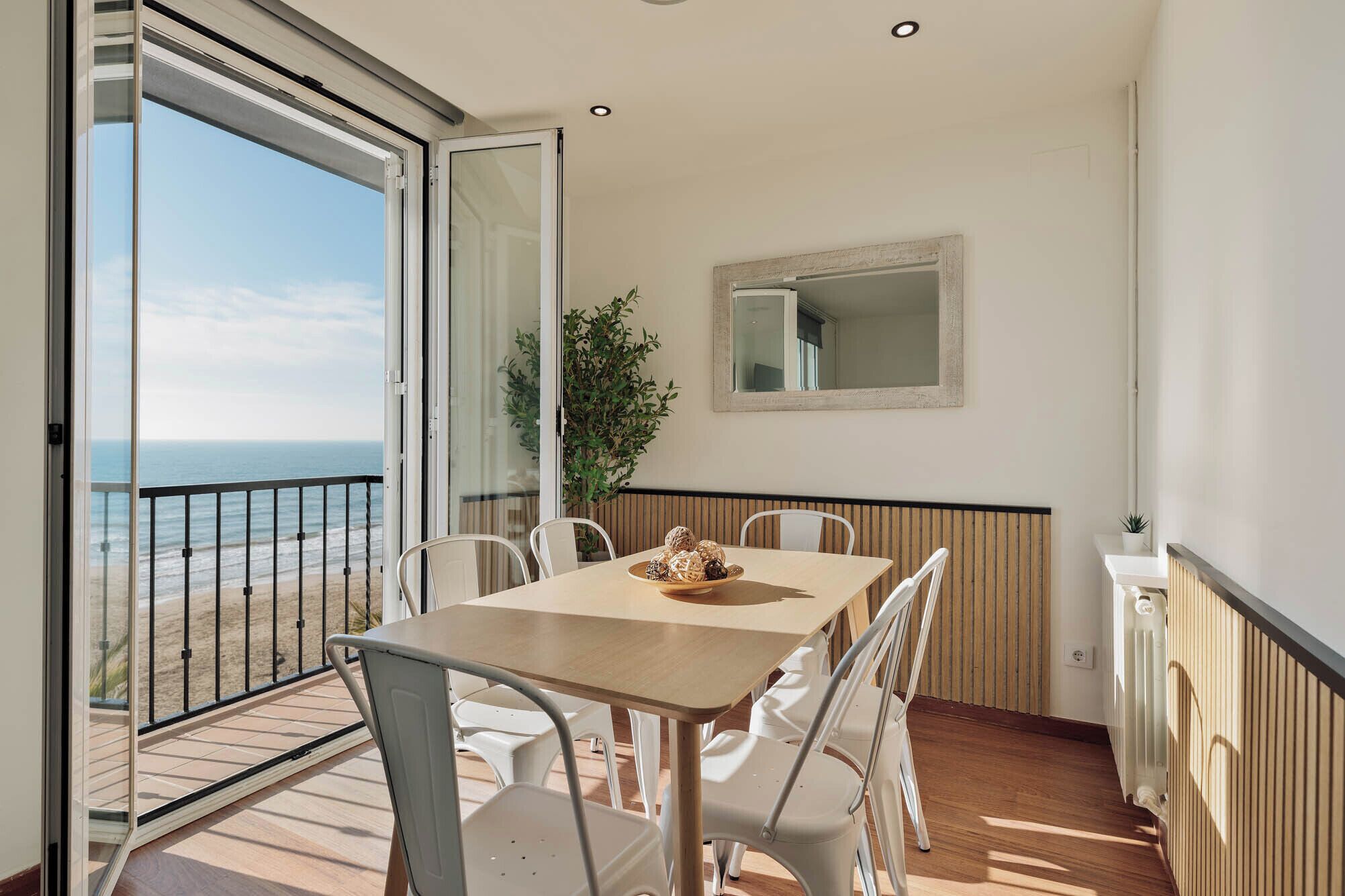 A balcony with a table and chairs, overlooking the sea.