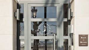 Entrada de un edificio moderno con puerta de vidrio, el número '57' en la parte superior y un cartel que dice 'Beach Dreams'.