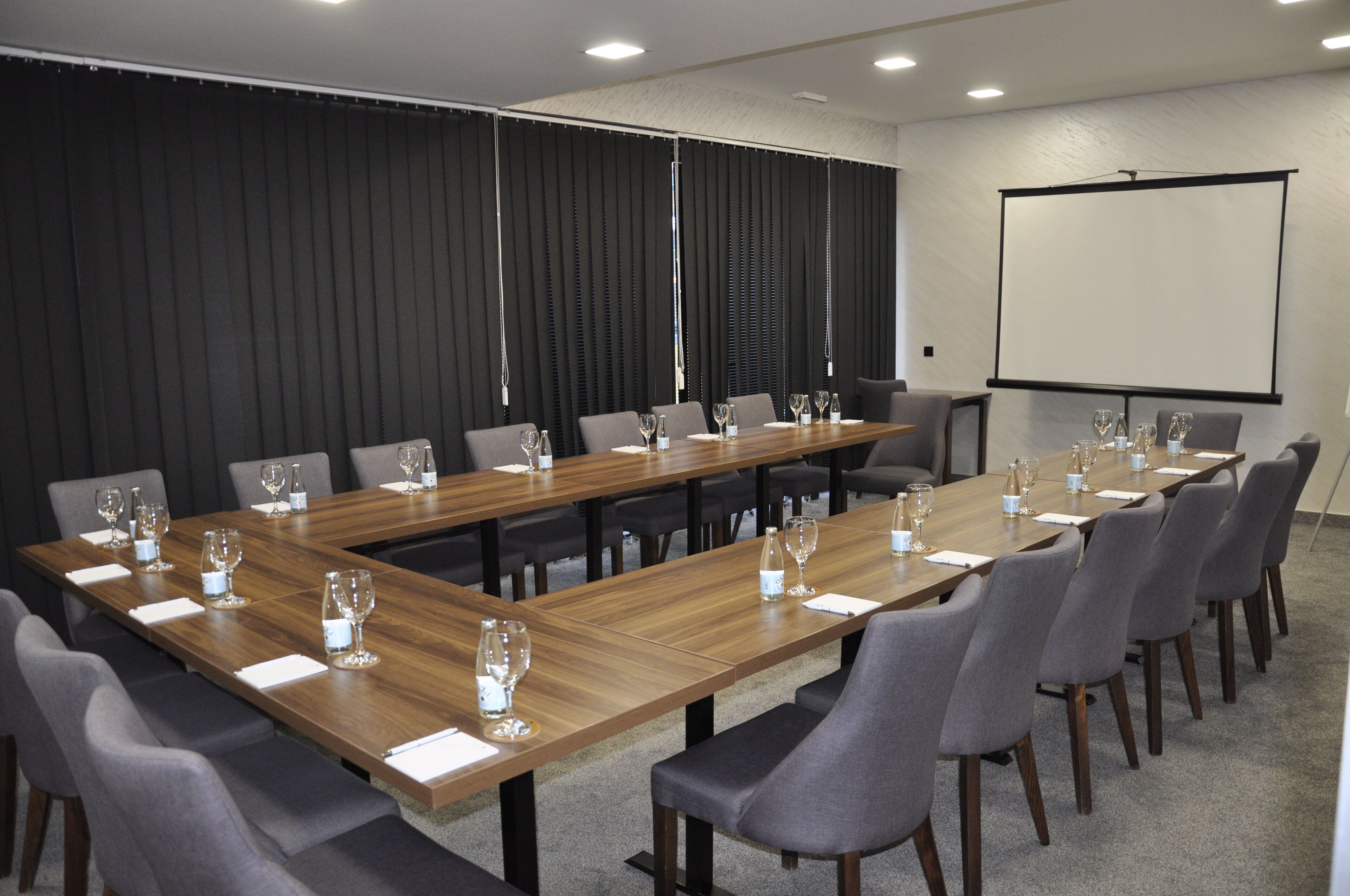 A conference room with a long table, chairs, and a projector screen.