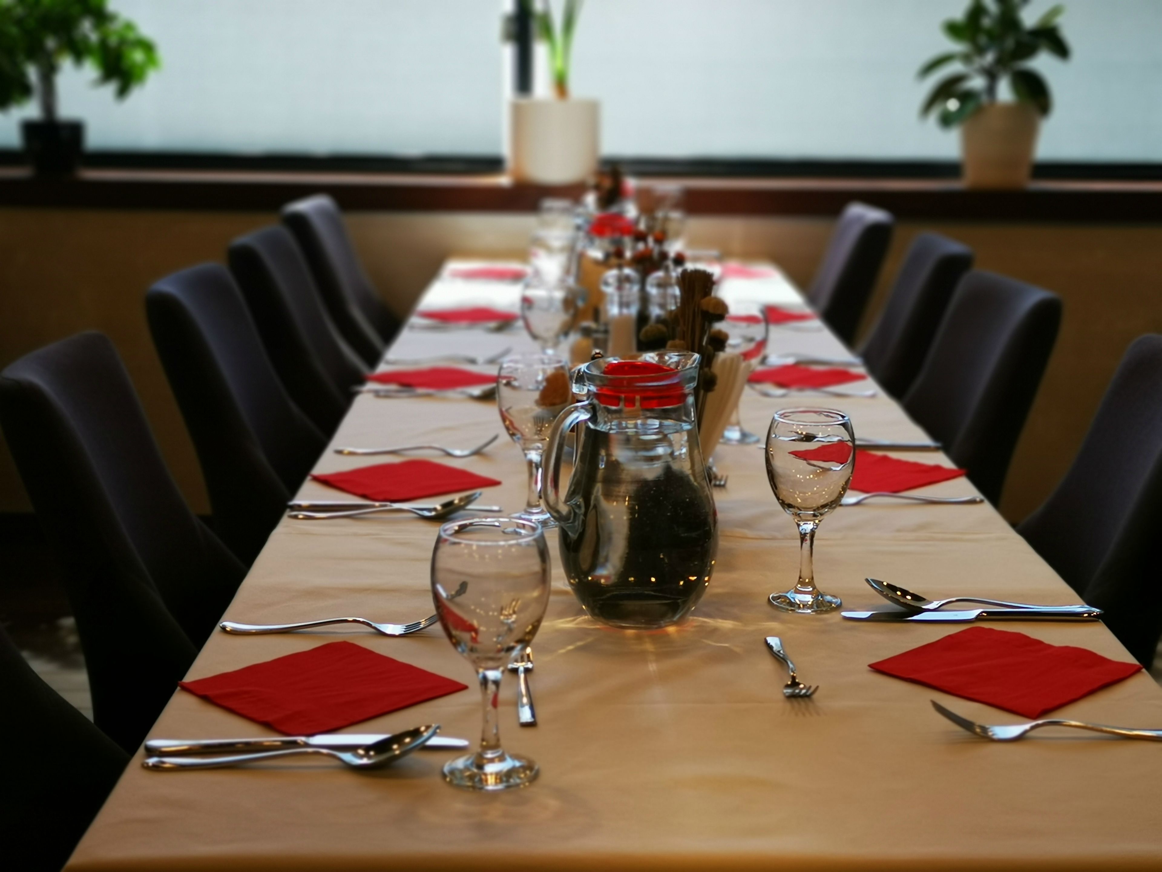 Uma longa mesa de jantar posta para uma refeição, com cadeiras em ambos os lados.