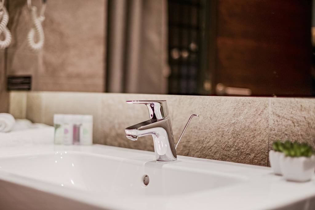 A modern bathroom with a chrome faucet, a white sink, and a marble wall.