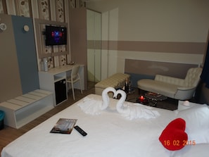 Una habitación de hotel con una cama, televisor, escritorio y sofá.