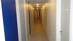 Un couloir étroit et bien éclairé, doté d’un plancher en bois et de murs aux couleurs claires.