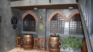 A room with stone walls, wooden barrels, and arched windows. - Castillo Medieval (Vina del Mar)