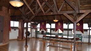 A spacious hall with wooden beams, a long table, and benches. - Castillo Medieval (Vina del Mar)