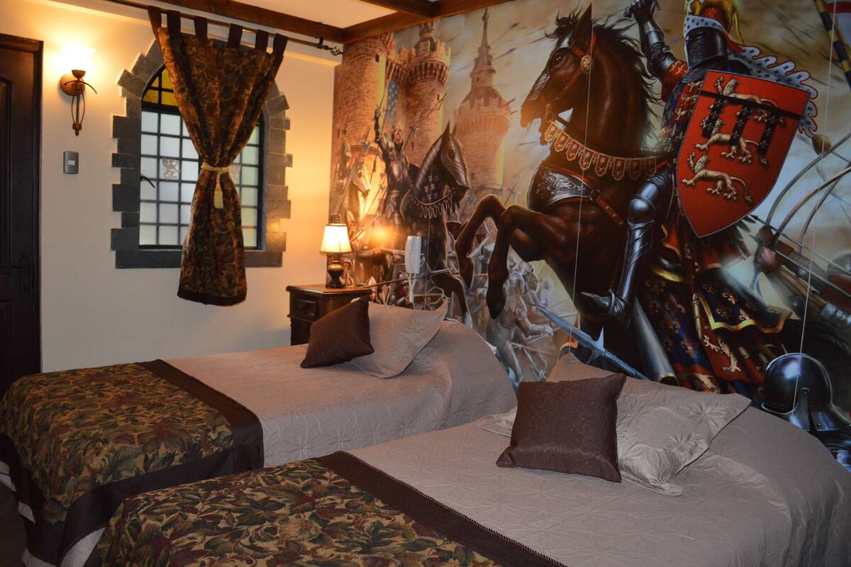 A bedroom with two beds, a large tapestry, and a castle-themed mural.