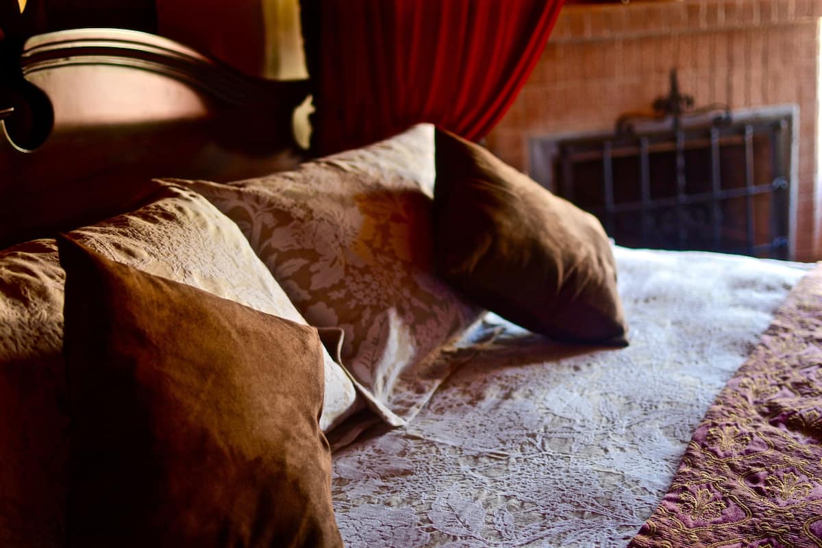 A bed with patterned bedding and a red curtain in the background.