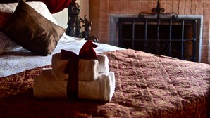 A bedroom with a bed, a fireplace, and a red curtain. - Castillo Medieval (Vina del Mar)