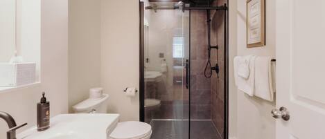 A bathroom with a shower, toilet, and sink.