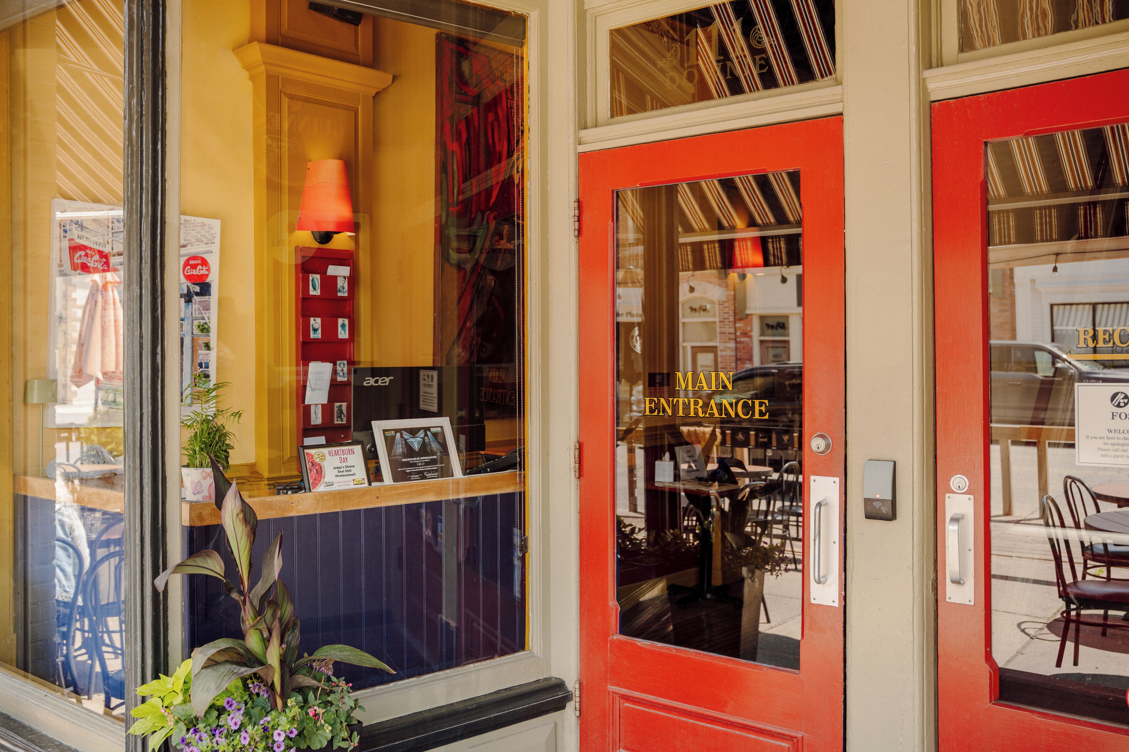 A hotel entrance with a red door, a reception desk, and a view of the interior.