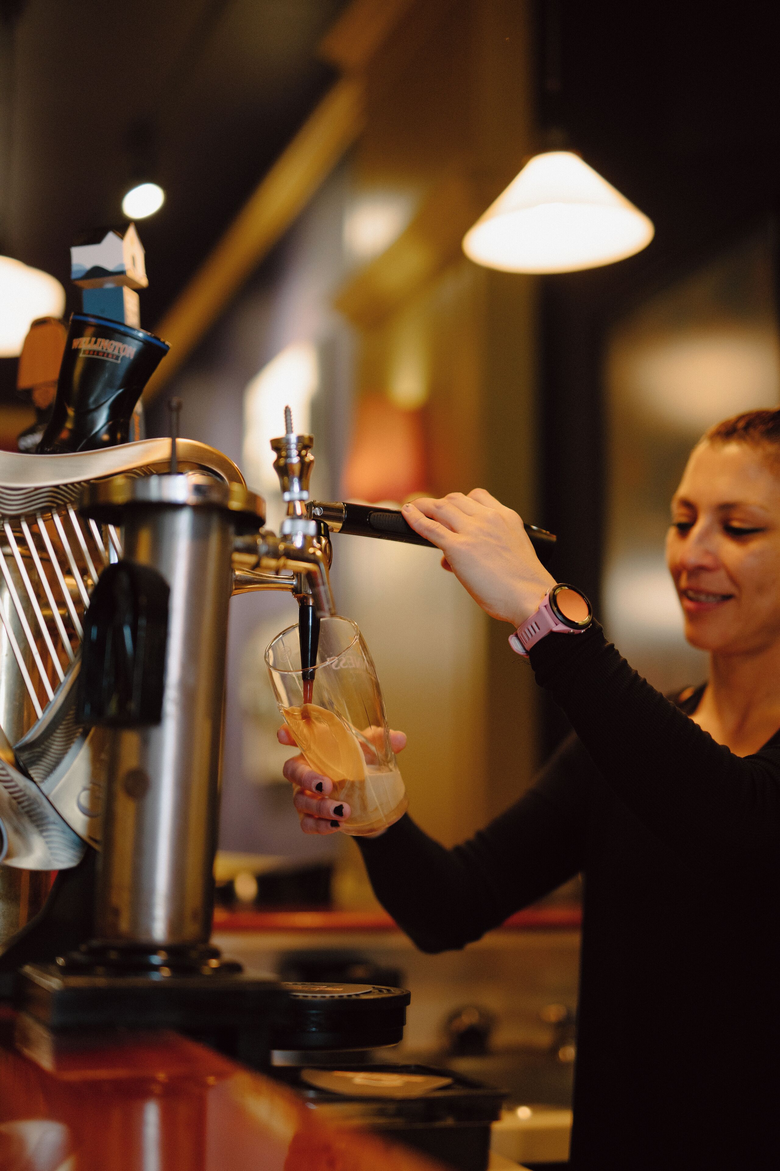 A person pouring a drink from a tap into a glass.