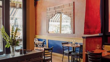 L’intérieur d’un restaurant, avec un plancher en bois, des meubles en bois foncé et une grande fenêtre donnant sur la rue.