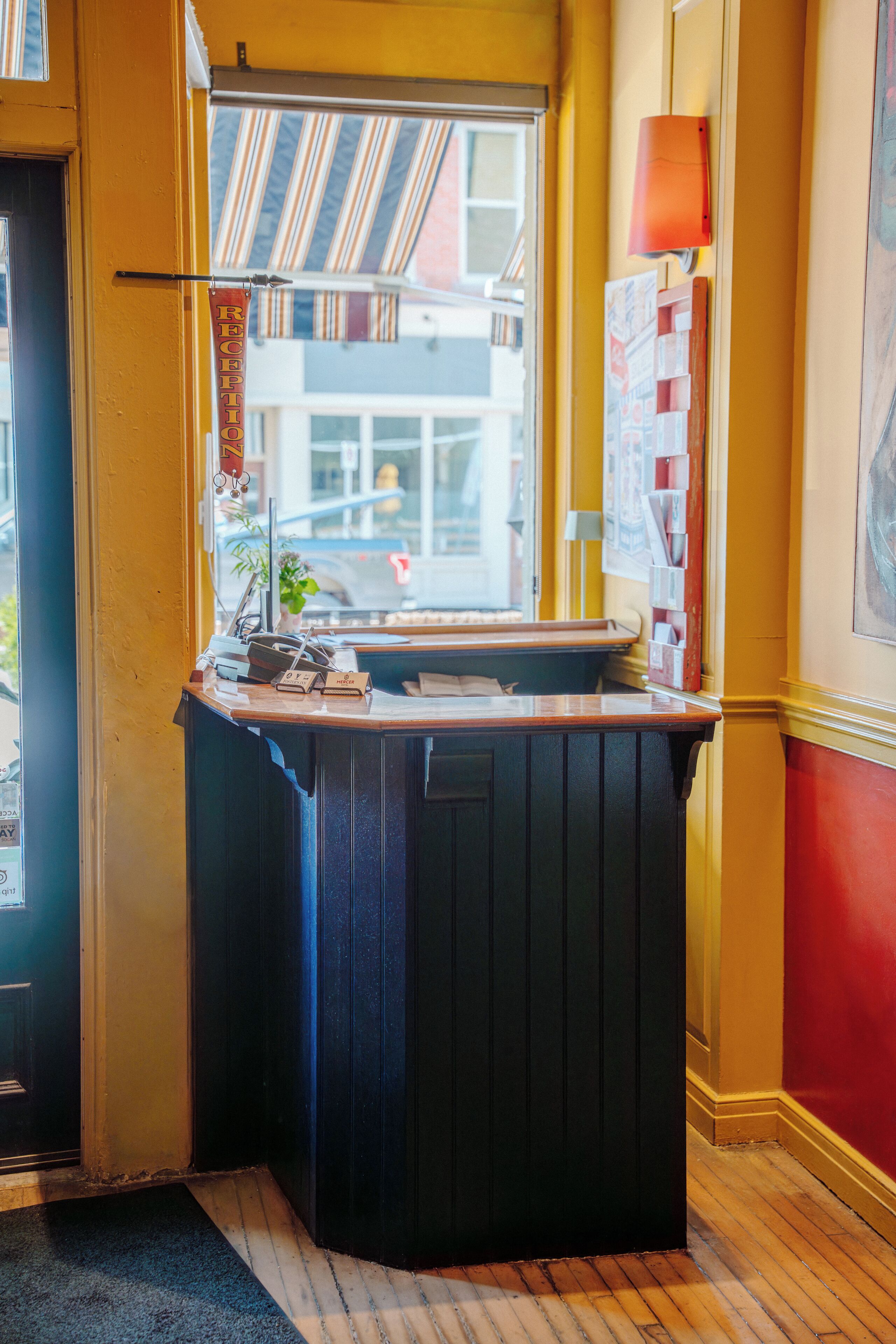 Un comptoir d’accueil avec vue sur l’extérieur, une porte et une lampe fixée au mur.