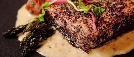 A plate of food with a steak, asparagus, and a creamy sauce.