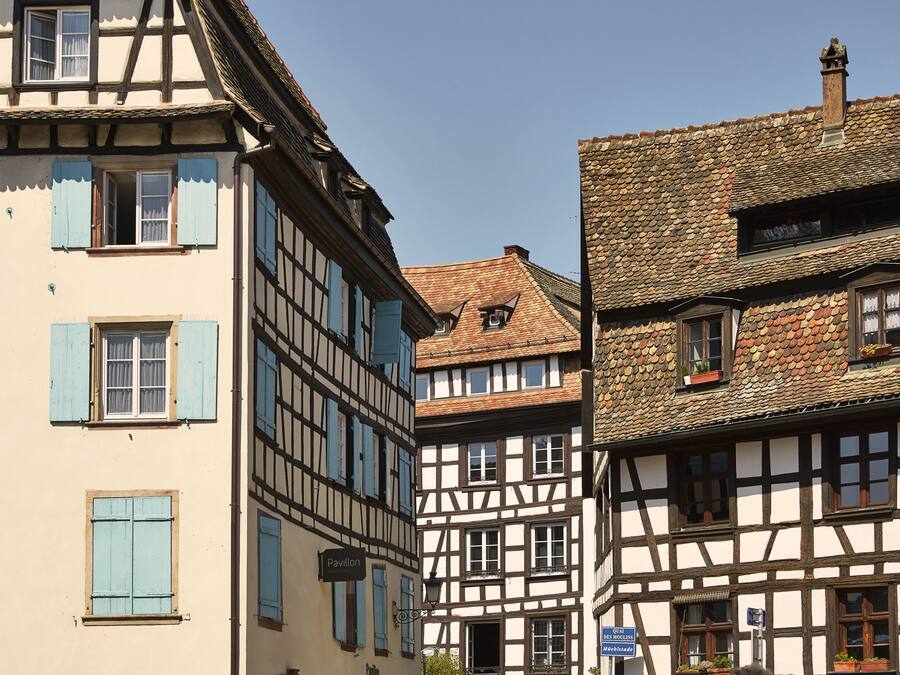 A row of traditional half-timbered buildings with multiple windows and shutters.