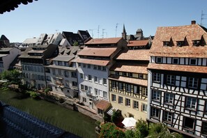 Een rij traditionele Europese gebouwen met steile daken en een rivier op de voorgrond.