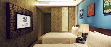 A hotel room with two beds, a TV mounted on a decorative panel, and a wall with framed artwork.