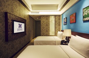 A hotel room with two beds, a TV mounted on a decorative panel, and a wall with framed artwork.