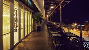 Een openluchtrestaurant met een overdekt terras, tafels en stoelen.