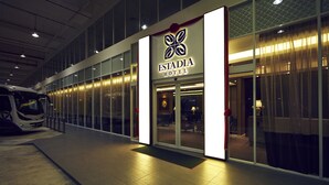 Het exterieur van Estadia Hotel, met een modern design, grote glasramen en een goed verlichte entree.