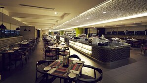 Een modern restaurant met een lange toonbank, meerdere tafels en een gedessineerd plafond.